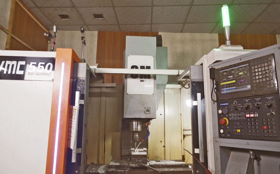 A CNC machine processes metal components at a machinery and equipment microenterprise.